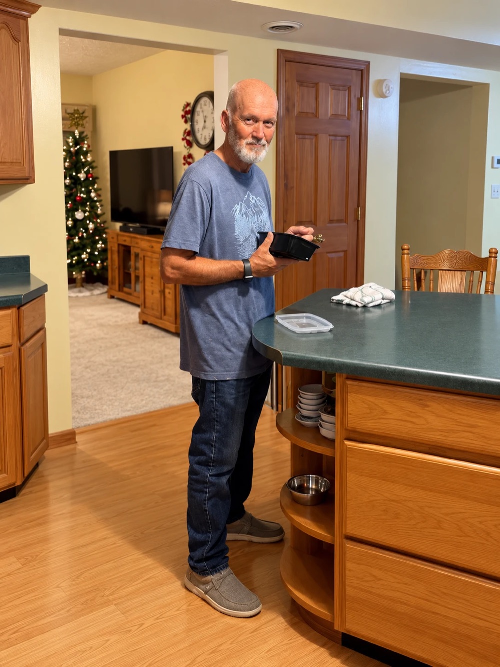 Dad standing at his kitchen counter holding a container of prepped food